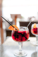 Red wine sangria glass with fruit and orange slice and straw on the table and soft background