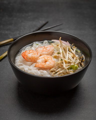 Asian Noodles with shrimps and seafood in black bowl