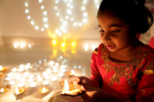 Little girl lighting earthen oil lamps on Diwali