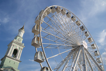 High Wheel carousel in the town square on the background of the summer blue sky