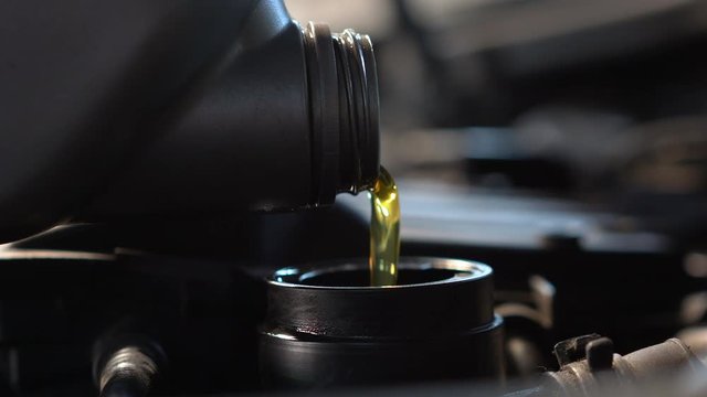 Pouring fresh new clean synthetic oil into car's engine