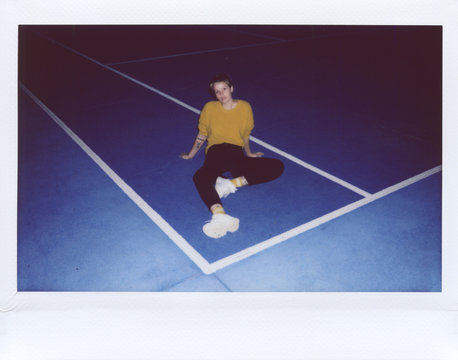 Stylish woman sitting on blue tennis court
