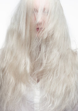 White haired model with long hair covering her face.