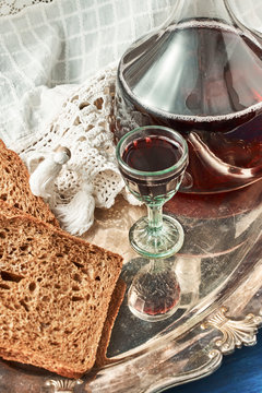 Slices of rustic bread and a carafe of red wine on a metal vinta