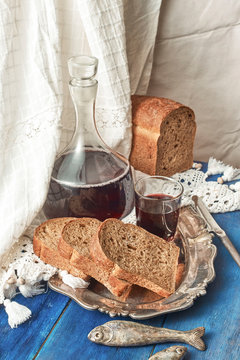 A carafe and a glass of red wine are slices of rye rural bread o