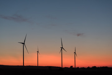 Four wind generators in the evening light, orange and blue sky, silhouette