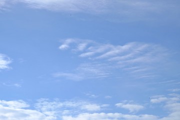 White fluffy clouds against blue sky in bright day for background texture 