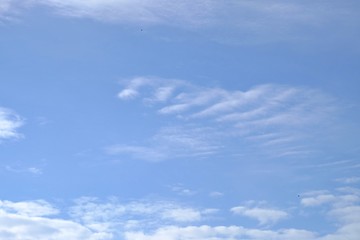 White fluffy clouds against blue sky in bright day for background texture 