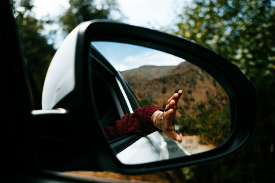 hand with tattoo seen from the rear-view mirror