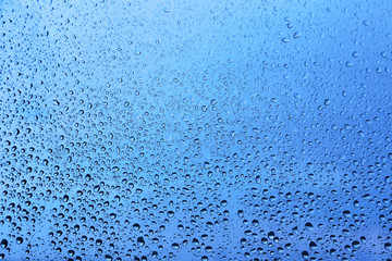 Water drops on glass, blue natural background