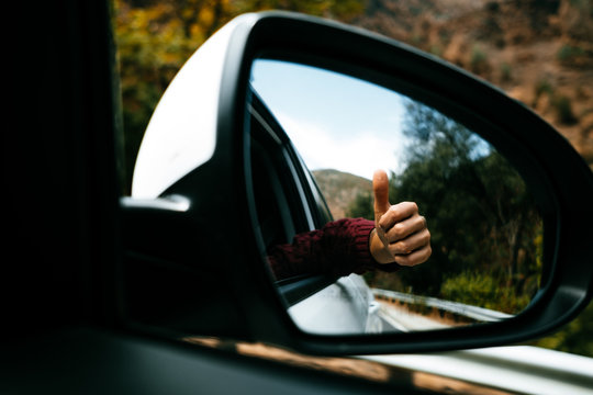 hand with tattoo seen from the rear-view mirror