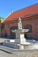 Fototapeta premium KALININGRAD, RUSSIA. The park Puttenbrunen fountain (Putti) against the background of the brick building of a warehouse