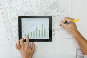 Crop man working with tablet and draft