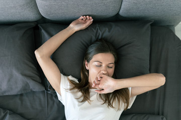 Naklejka premium Young adult woman sleeping on bed in morning