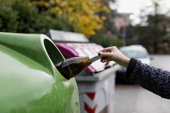 Woman throwing empty bottle in garbage can