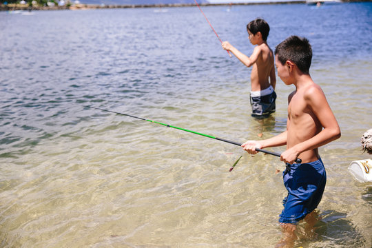 Two boys fishing for minnows in the ocean along the coastline of Hawaii