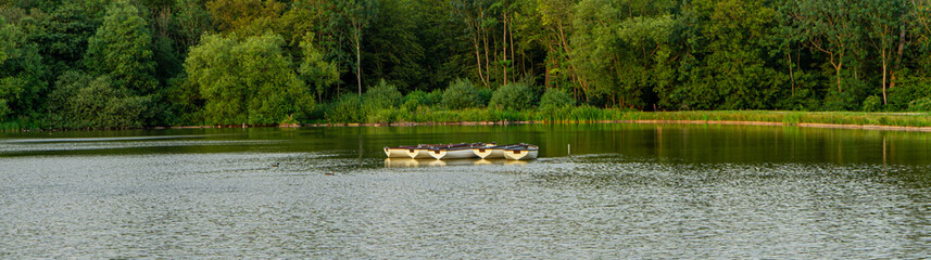 panoramic shot of rowing boats on a lake with reflections and contrasting sky