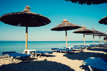One row with straw umbrellas on a beautiful beach in Greece and no people Selective focus