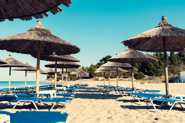 Straw umbrellas in rows with on a beautiful beach in Chalkidiki and no people Selective focus