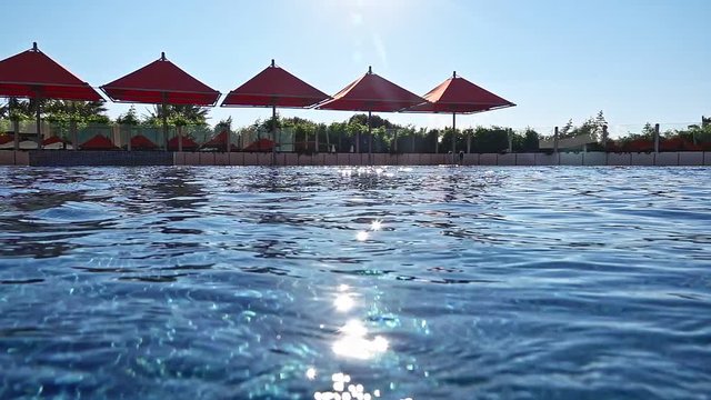 Swimming Pool.This is a slow-motion stock video that consists of stunning footage of a beach chair and umbrella near a swimming pool.