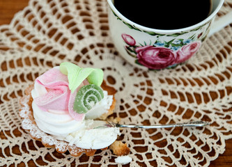 cake with cream, a cup of black coffee and a silver spoon on a napkin. delicious dessert