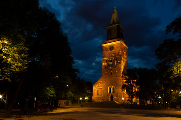 Night view of the square and the tower of the Cathedral of the 13th century with illumination against the background of a summer, dark, night sky. Turku city, historical landmark of Finland.
