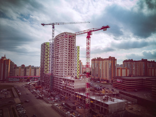 Building crane and building under construction. Construction site. Construction cranes and high rise building under construction against cloudy sky