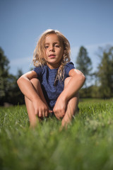 Little girl sitting on grass in a field