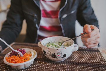 Cold soup with fresh cucumbers, radishes, potato and sausage with yoghurt in bowl. Salads from fresh vegetables: cabbage, carrots, beets in a white plastic plate.