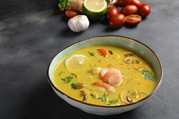 Tom Yam kung Spicy Thai soup with shrimp, seafood,tomatoes, mushrooms, lemongrass, coconut milk, ginger and chili pepper in bowl . Traditional Thai food