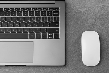 Workplace with open laptop with black screen and mouse on modern grey stone desk, filtered image, focus on keyboard.Office table with notepad, computer. copy space. horizontal photo