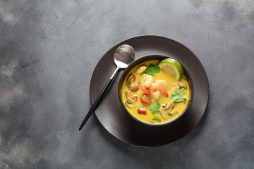 Tom Yam kung Spicy Thai soup with shrimp, seafood,tomatoes, mushrooms, lemongrass, coconut milk, ginger and chili pepper in bowl . Traditional Thai food