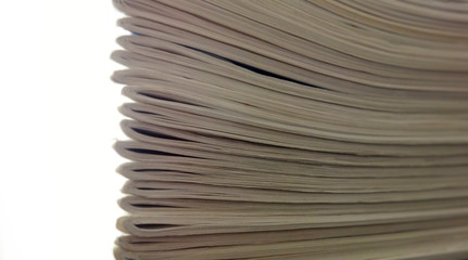 Stack of papers, white-sheet magazines focused on edge with light and blur.