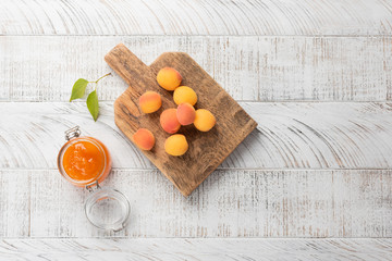 Jars with apricot jam on white wooden background