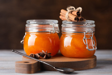 Jars with apricot jam on dark background