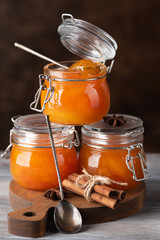 Jars with apricot jam on dark background