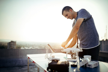 Young technician flying UAV drone with remote control on rooftop