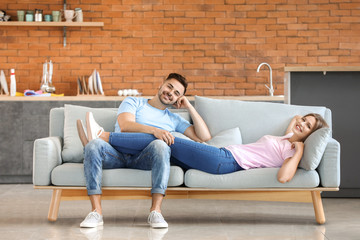 Happy young couple resting together on sofa at home