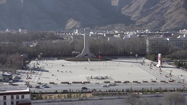 Chinese national flag waves on square in front of Potala Palace (not visible), with army barracks and base in the background in Lhasa