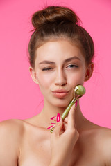 Woman applying jade roller for massaging her face