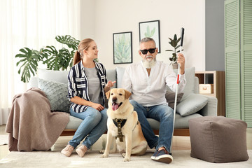 Blind mature man with daughter and guide dog at home