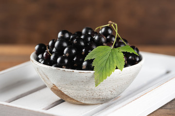 Black currant in bowl on wooden background