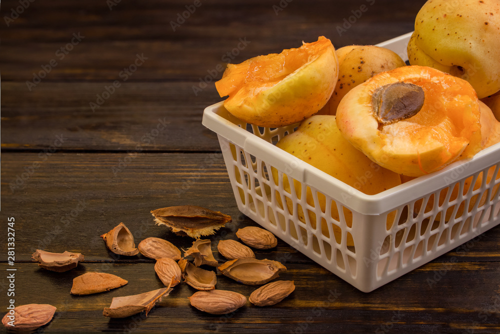 Wall mural whole apricots and halves in a basket, on a wooden table with broken apricot pits. food concept.