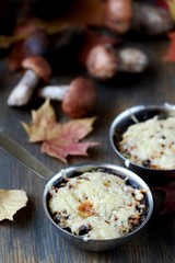 Julienne with forest mushrooms. Mushrooms are baked in cream and with cheese. Autumn leaves.