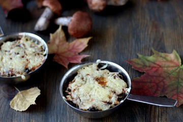 Julienne with forest mushrooms. Mushrooms are baked in cream and with cheese. Autumn leaves.