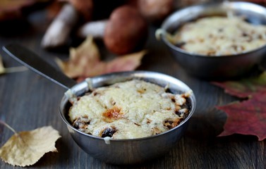 Julienne with forest mushrooms. Mushrooms are baked in cream and with cheese. Autumn leaves.