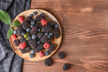 Plate with tasty berries on wooden table