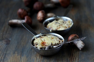 Julienne with forest mushrooms. Mushrooms are baked in cream and with cheese. Autumn leaves.