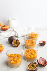 Caramel panna cotta, custard pudding with peach and passion fruit, white table, copy space