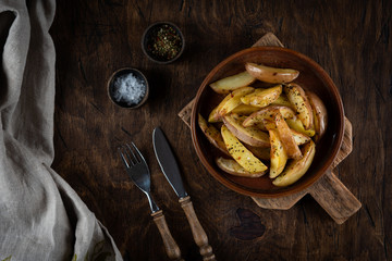 Baked potato in a plate on a wooden background, top view